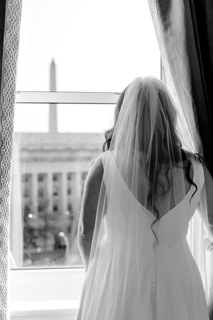 Bride looks out of window at The Willard Intercontinental in DC and sees the National Monument - DC wedding photo.