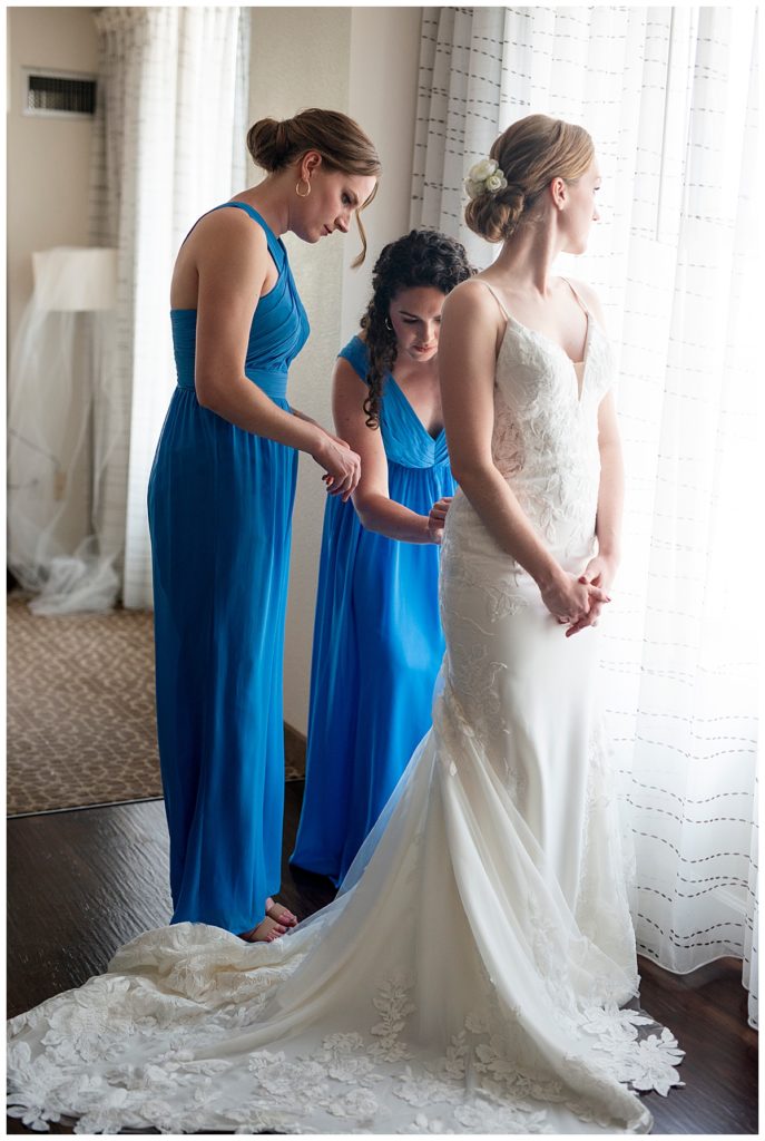 Bridesmaids help bride with her gown at DC hotel before her wedding.