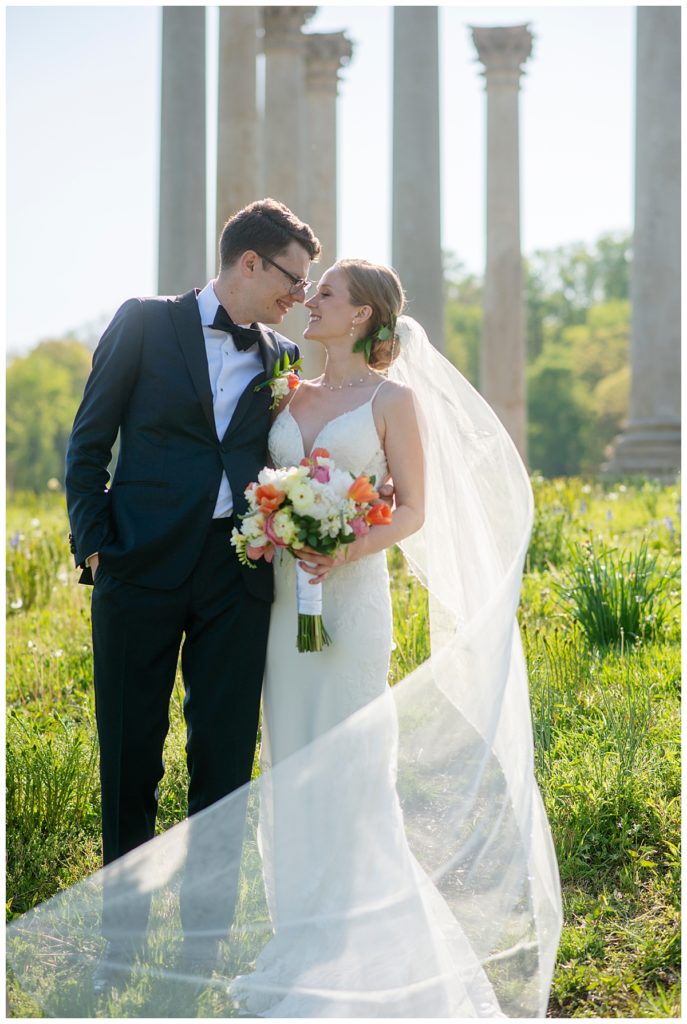Wedding couple poses in front of The National Capitol Columns at wedding venue in DC.
