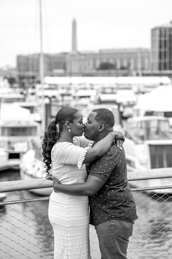 The Washington Monument is visible from the pier at The Wharf for a couple's engagement photo.