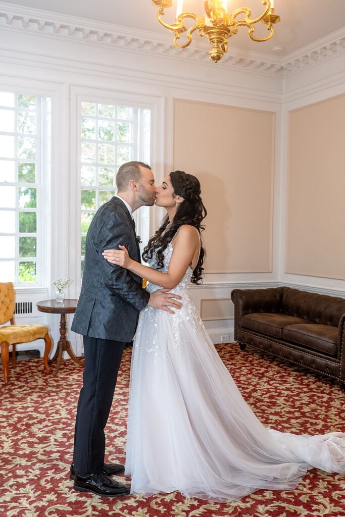 Couple kiss after first look inside Grey Rock Mansion wedding venues in Maryland