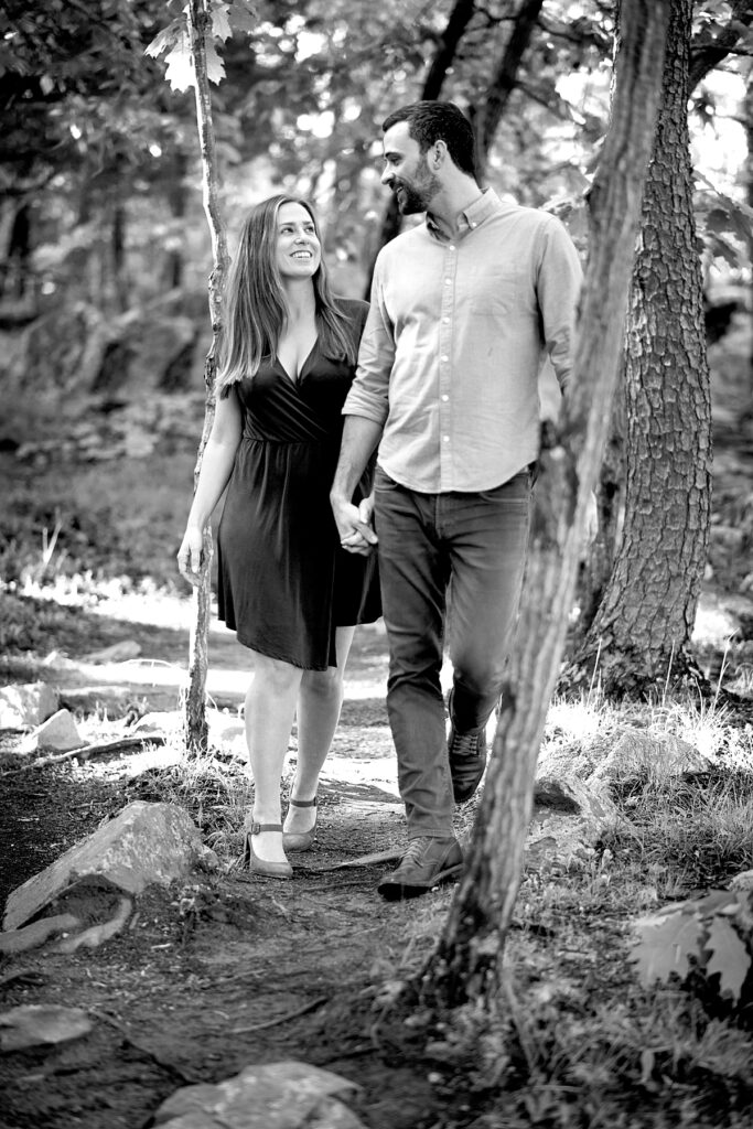 Couple walk in woods at Great Falls Park for engagement photos.
