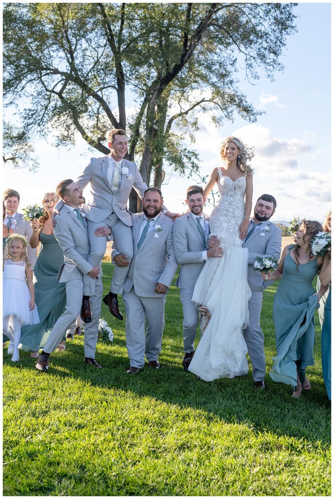 Wedding party lifts up bride and groom