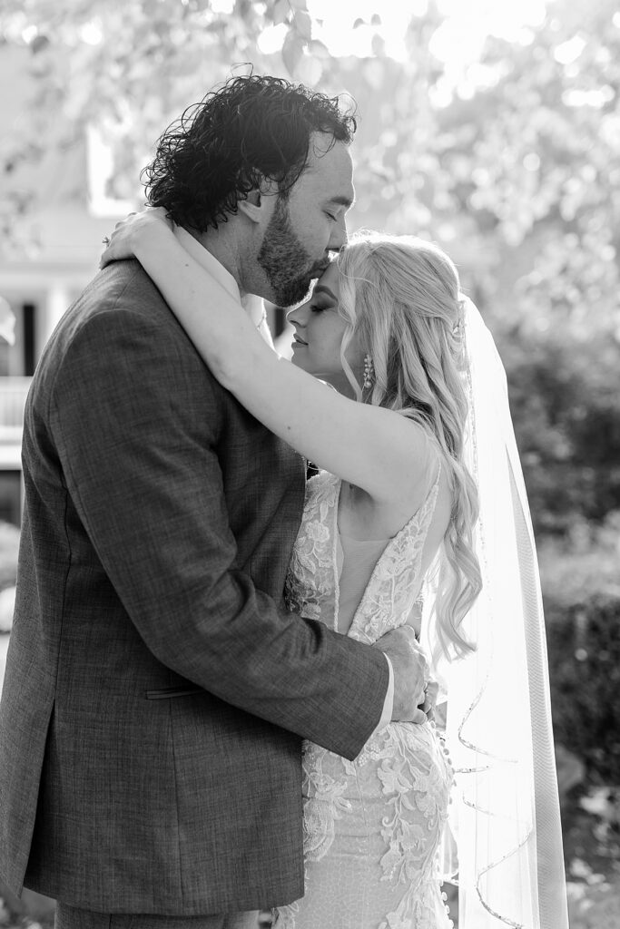 Groom kisses his bride's head outside the cottage at Kurtz Beach.