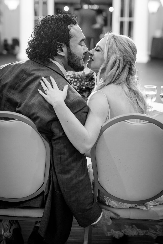 Bride and groom kiss at their sweetheart table inside the Bay Room at Kurtz Beach in Maryland