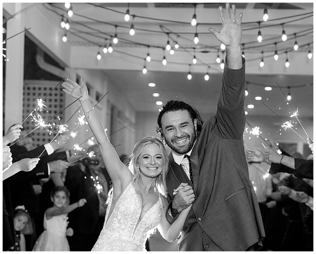 Bride and groom wave farewell to their Maryland wedding photographer in sparkler sendoff with guests