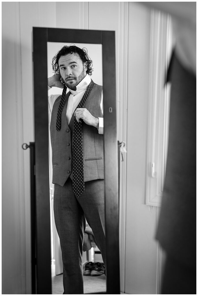 Groom checks his hair in the mirror as he gets dressed for his wedding