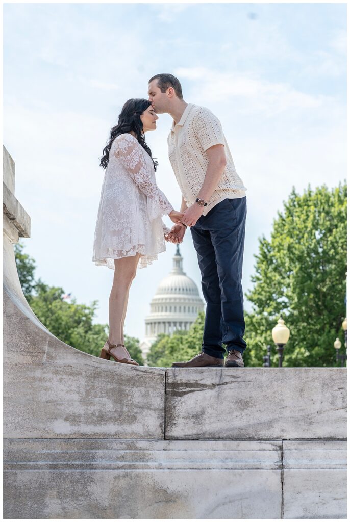 Engaged couple kiss with U.S. Capitol in the background