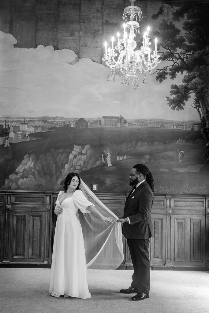 Bride and groom stand in front of historic hand paintings of early Baltimore.