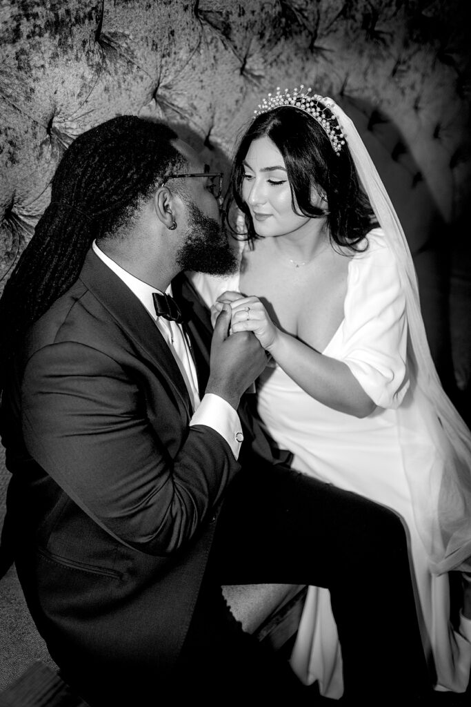 Bride and groom hold hands in a booth at The Owl Bar on their wedding day.